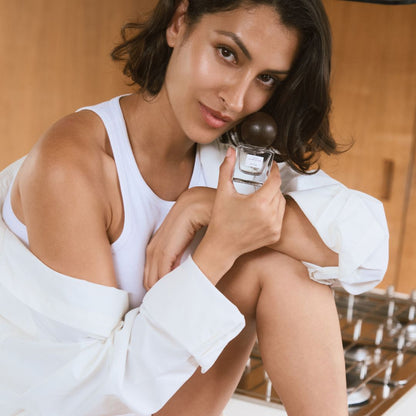 Model holding a perfume bottle in a kitchen setting