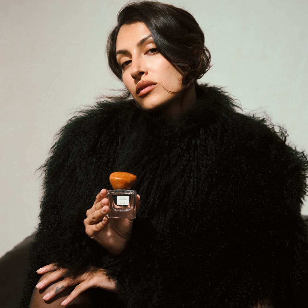 Woman holding a perfume bottle with a neutral background