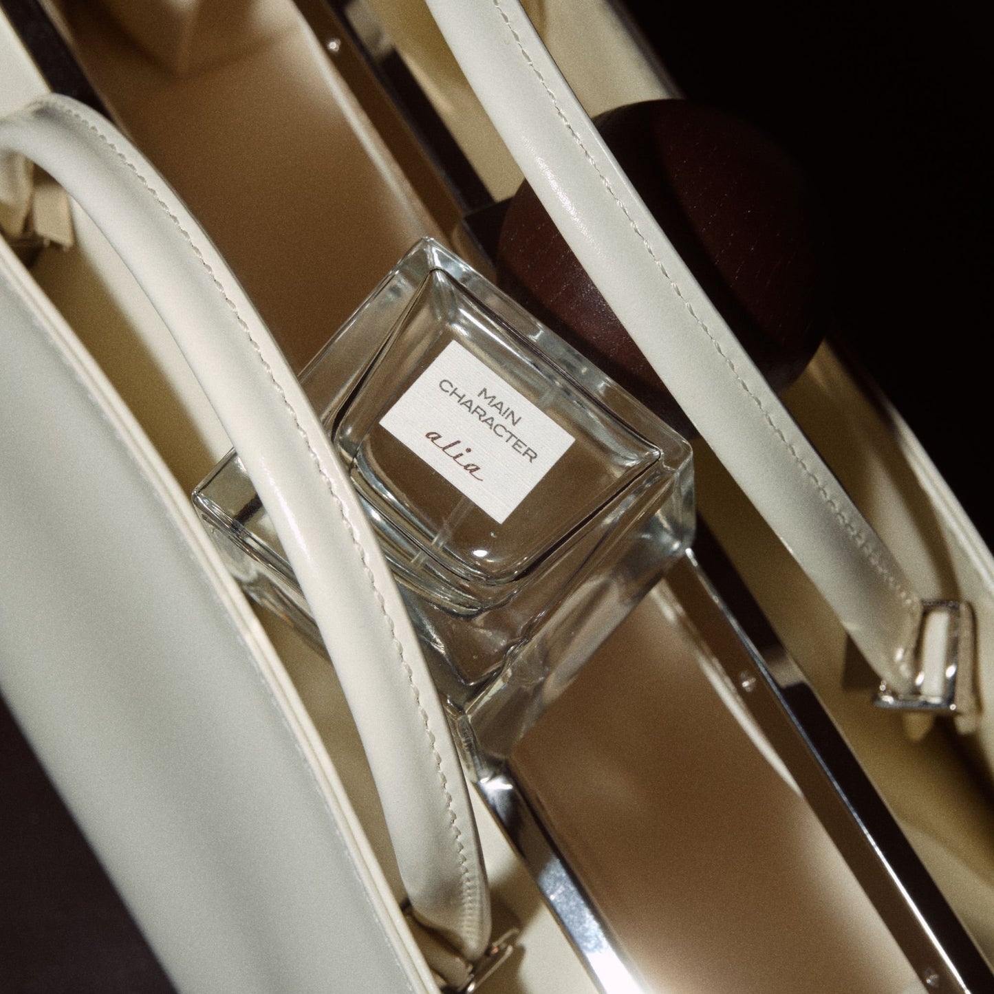 Main Character Alia fragrance resting on white leather bag