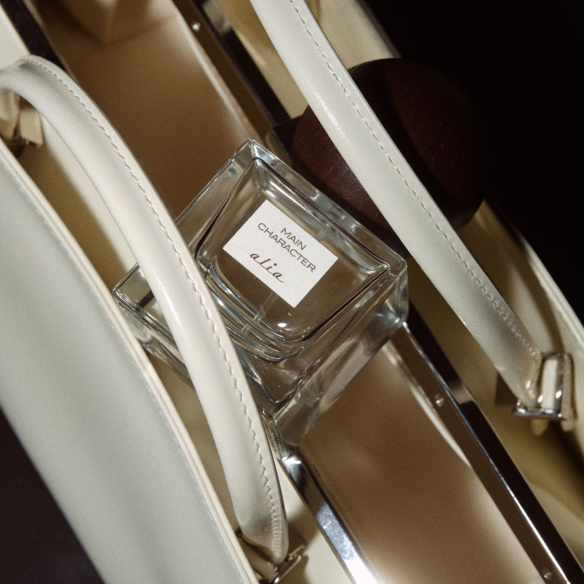 Main Character Alia fragrance resting on white leather bag