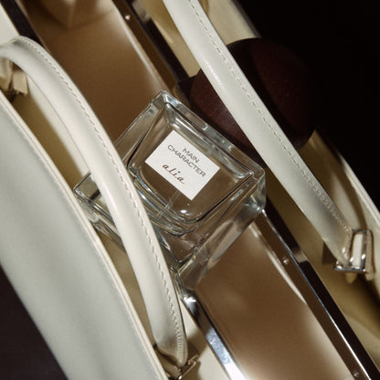 Main Character Alia fragrance resting on white leather bag