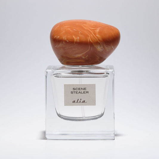 Clear perfume bottle of 'Scene Stealer' on a light gray background