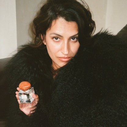 Model holding a bottle of 'Scene Stealer' with a blurred background