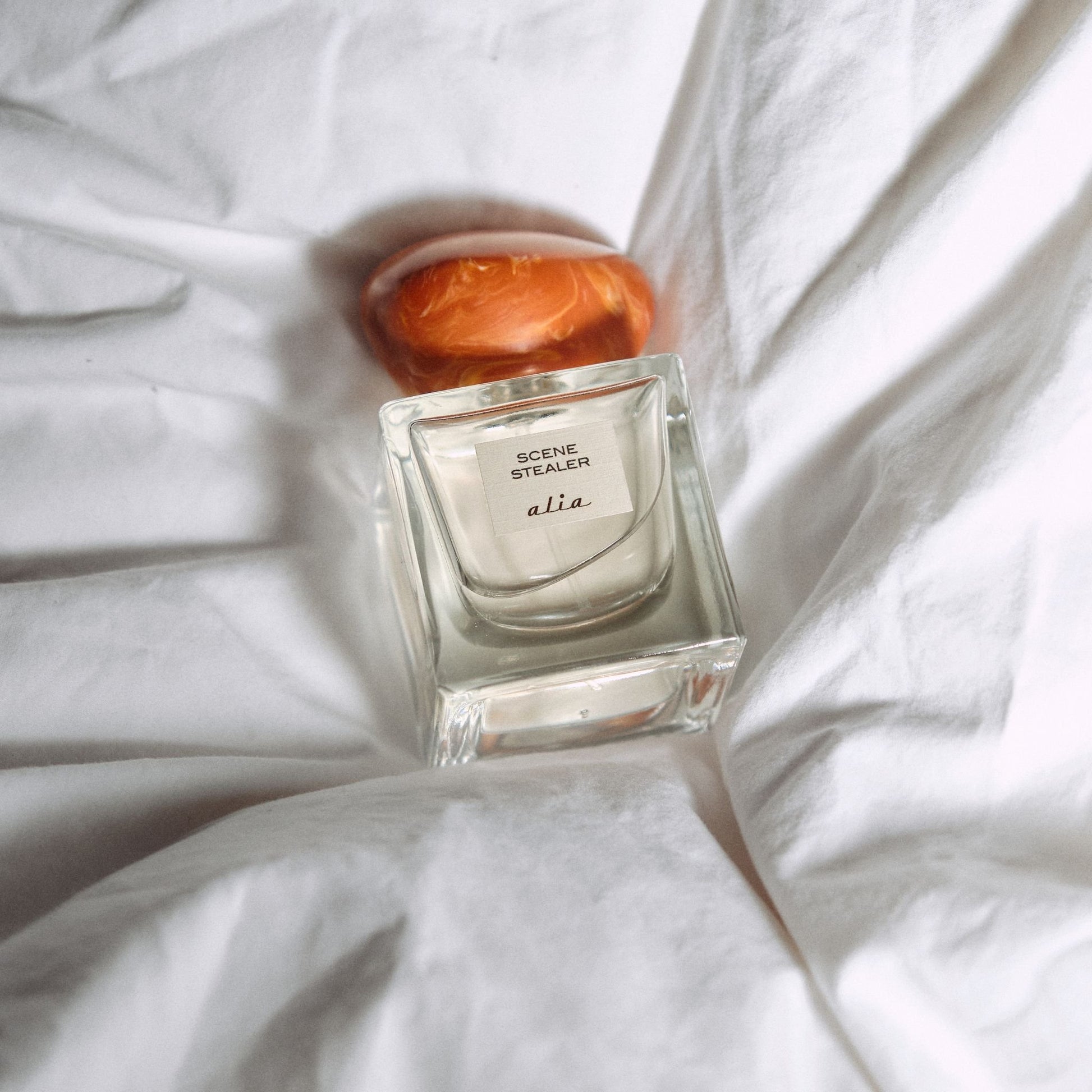Scene Stealer perfume bottle on a white fabric background
